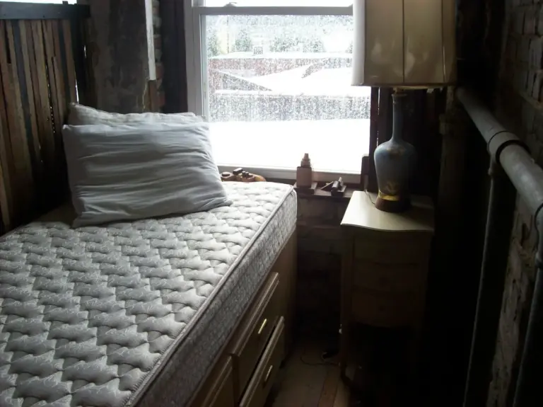 Mattress and pillow on a bed beside a window